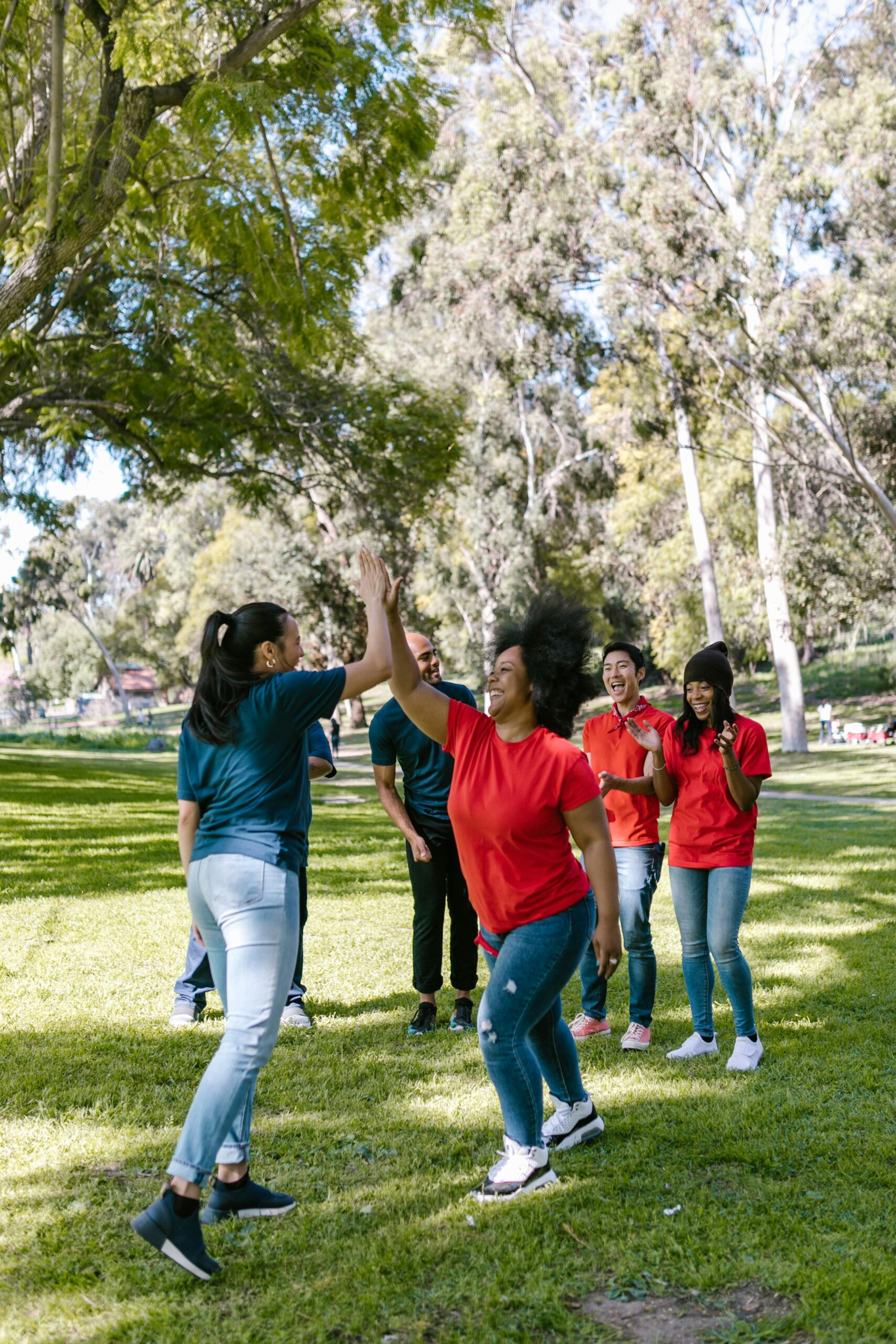 A diverse group enjoying team-building activities outdoors in a sunny park.